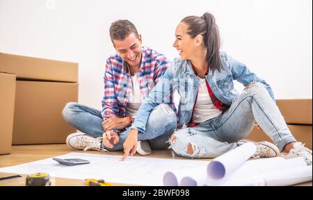 Happy couple moved in to a new house having fun while planning on the interior design. Stock Photo