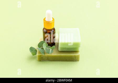 Soap, eucalyptus and serum on green backgriund. Skin care. Minimalism Stock Photo