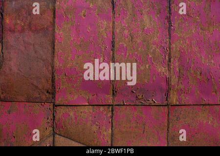 rusted tin sheets patchwork wall texture and flat background with peeling leftovers of pink paint Stock Photo