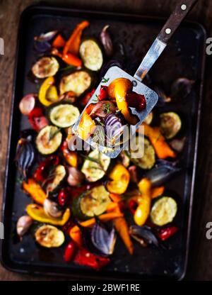 Oven Roasted Vegetables on Spatula and Tray with herbs Stock Photo