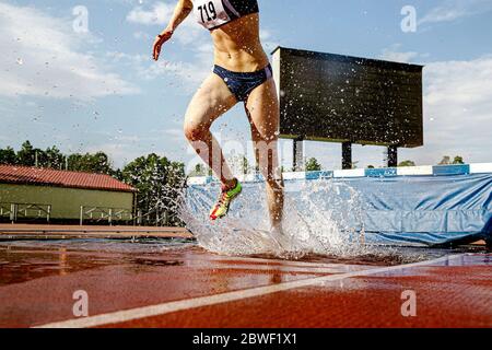 women athlete steeplechaser run pit with water in steeplechase race Stock Photo