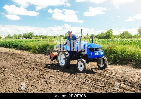 A farmer rides across the field on a tractor with a milling machine. Ground preparation for crop planting. Loosening surface, cultivating land for pla Stock Photo