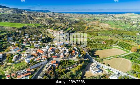 Aerial bird's eye view of Goudi village in Polis Chrysochous valley, Paphos, Cyprus. View of traditional ceramic tile roof houses, church, trees, hill Stock Photo