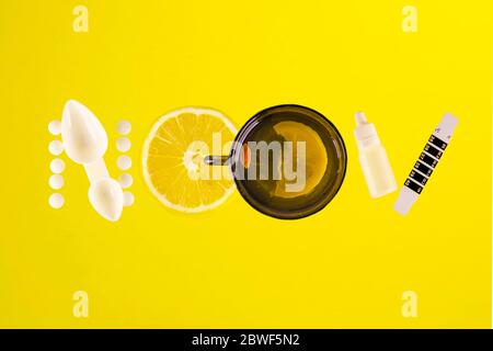 Various medications, a thermometer, sprays for nasal congestion and sore throat are laid out in the form of an NCOV inscription on a yellow background Stock Photo