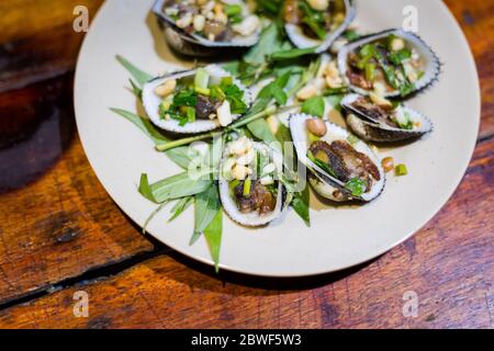 Delicious fresh prepared mussels, clams. Traditional vietnamese cuisine served in harbour restaurant on Phu Quoc, Vietnam. Stock Photo
