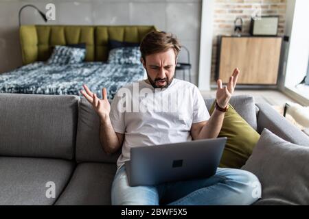 Outraged angry man reading bad news, looking at screen, having problem with broken laptop Stock Photo