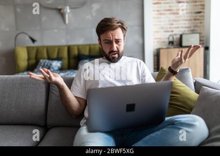 Outraged angry man reading bad news, looking at screen, having problem with broken laptop Stock Photo