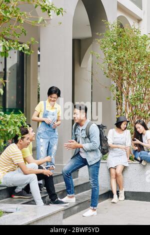 Vietnamese college students talking and resting in backyard of campus during break Stock Photo