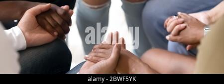 Multiethnic people sit in circle holding hands during therapy session Stock Photo