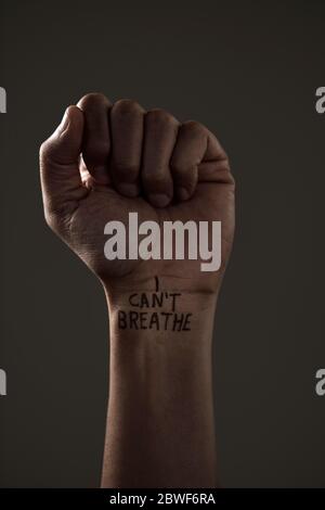 closeup of the raised fist of a man with the text I cant breathe in his wrist, as it is used as slogan in the George Floyd protests in response to pol Stock Photo