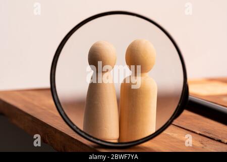 Two wooden figures of people through magnifying glass. Search of love concept Stock Photo