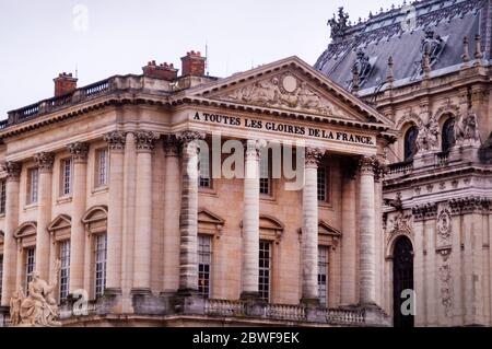 Entablature of Versailles in France is engraved with 'To All the Glories of France' and a sculpture, La Paix, or Peace is in the foreground. Stock Photo