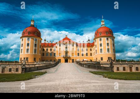 Yellow Facade of Castle Moritzburg with orange roof, Saxony, Dresden, Germany. Beautiful spring day with blue sky and white clouds. Surrounded by Stock Photo