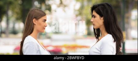 Two Girls Having Confrontation Standing Outside In Park, Panorama Stock Photo