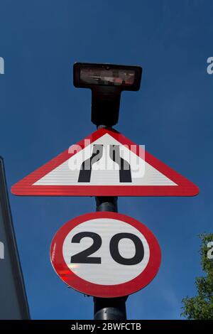 british road signs indicating the road narrowing ahead and a 20mph speed limit Stock Photo