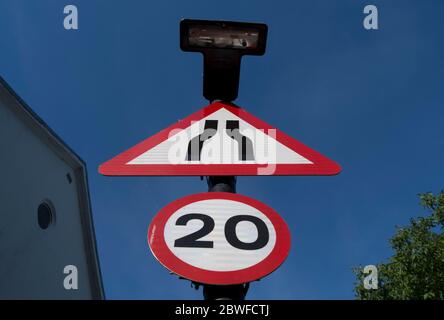 british road signs indicating the road narrowing ahead and a 20mph speed limit Stock Photo