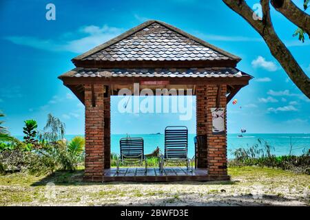 Giant stunning coconut palm tree with a massage hut and deck chairs under the beautiful blue sky on the shores of the sandy beautiful exotic and stunn