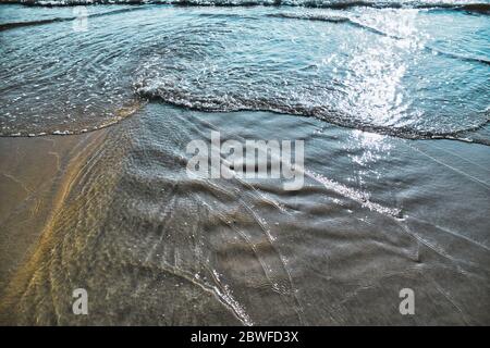 Water of the Andaman sea is forming different shapes when reaching the sandy Cenang beach of Langkawi Stock Photo