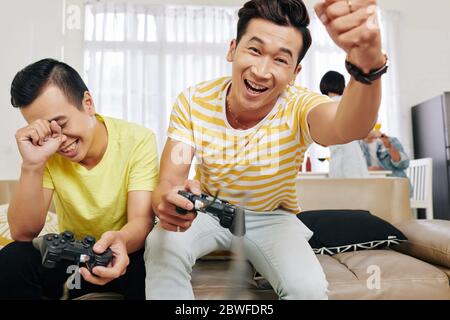 Excited young Vietnamese man celebrating his victory in video game Stock Photo
