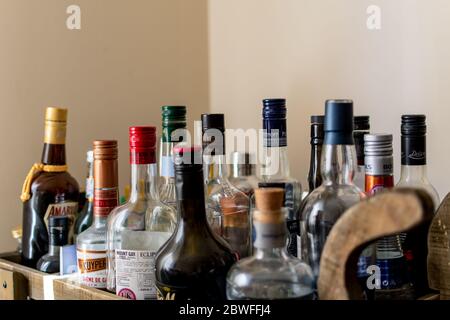 Many bottles of alcohol for cocktail making on a bar cart at home Stock Photo