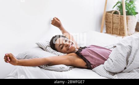 African american girl stretching her body in bed Stock Photo