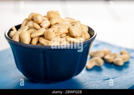 Cashew in a ceramic bowl on a white wooden background. Stock Photo
