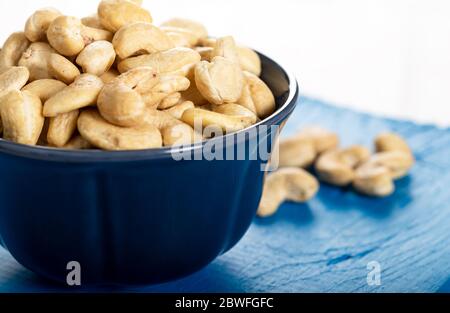 Cashew in a ceramic bowl on a white wooden background. Stock Photo