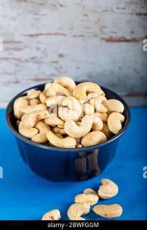 Cashew in a ceramic bowl on a white wooden background. Stock Photo