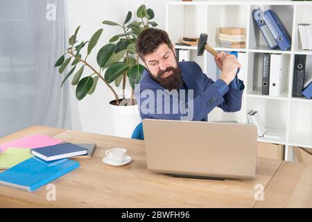 hate my job. dealing with error. overworked man crush laptop with hammer. frustrated computer user. businessman express anger. ready to smash. Office life makes him crazy. Slow internet connection. Stock Photo