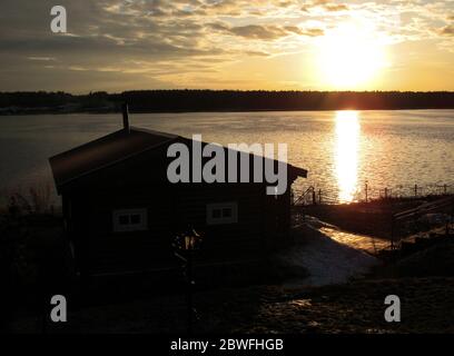 Wooden house on the river. Sunset, spring. House on the river with sunset view. Evening sunrise on a choppy river wind early spring landscape. Sunset Stock Photo