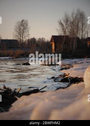 Wooden house on the river. Sunset, spring. House on the river with sunset view. Evening sunrise on a choppy river wind early spring landscape. Sunset Stock Photo