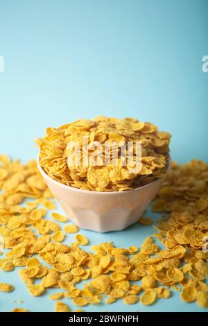 Cereal (cornflakes) for breakfast in a pink bowl on a blue background. Minamal art creative food concept Stock Photo
