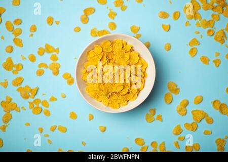 Cereal (cornflakes) for breakfast in a pink bowl on a blue background. Minamal art creative food concept Stock Photo