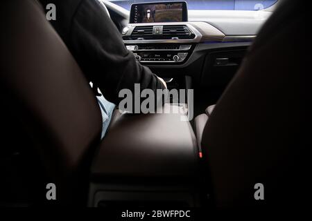 view from the back seat of a modern premium car. leather chairs. the driver sits behind the steering wheel, in front of him is the front panel with Stock Photo
