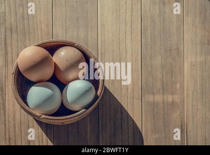 Four eggs in a wooden bowl on a wooden table. Copy space. Stock Photo