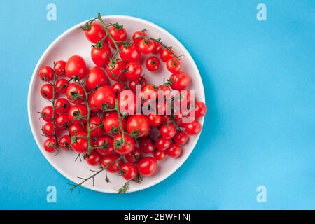 Bunch of bright fresh red cherry tomatoes on round plate Stock Photo