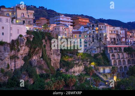 Tropea, Italy - September 9, 2019: Evening view on old ancient town on mountain rock. Buildings and street lights with dusk sunlight color. Stock Photo