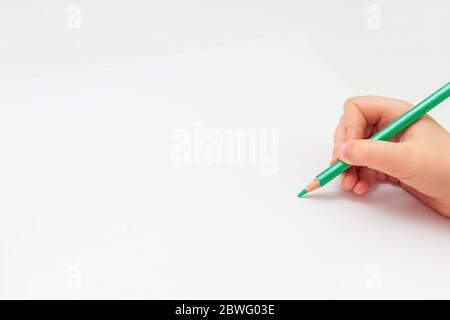 Top view of baby's hand drawing with green pencil on white paper with the  set of colour pencils. Kids painting concept. Copy space for text. Mockup  Stock Photo - Alamy