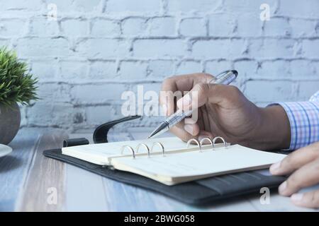 person hand writing on notepad at office desk  Stock Photo