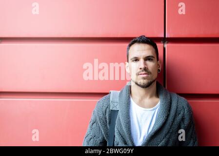 Front view of a fashionable young man standing against red wall Stock Photo