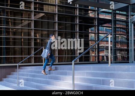 Young bearded man walking upstairs to workplace in an office building Stock Photo