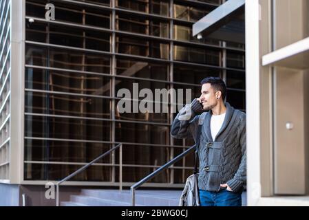 Man using smartphone outdoors, standing next to office building Stock Photo