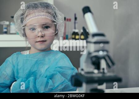 Little adorable girl makes scientific experiments with chemical and biological products in her home laboratory. Stock Photo