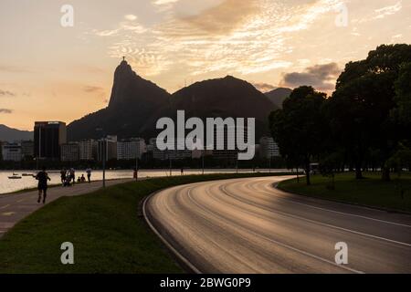 Beautiful sunset view to empty highway during covid-19 corona virus outbreak, Christ the Redeemer statue on top of Corcovado Mountain on the back, Rio Stock Photo