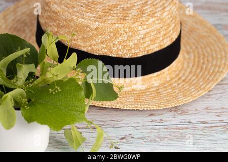 bouquet of linden flowers with a straw hat. Top view, copy space. Stock Photo