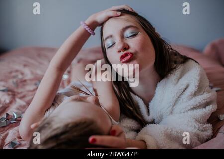 Sisters laying on bed making goofy faces together Stock Photo