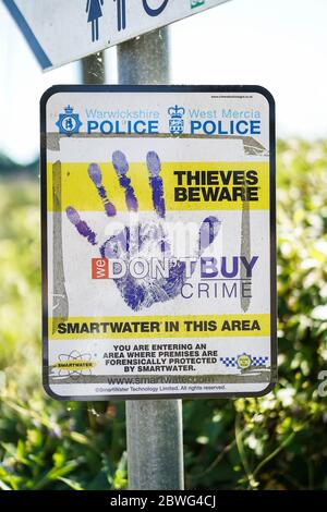 Thieves Beware UK police sign isolated outdoors on post in UK countryside. Signage warning We don't buy crime, Premises protected by Smartwater. Stock Photo