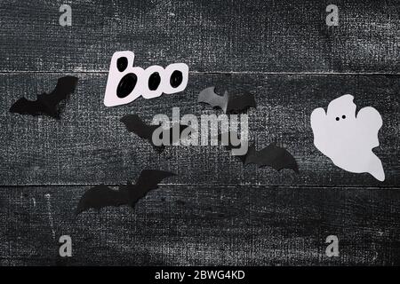 White ghost costume on dark black wooden background. Minimalistic Halloween concept. craft paper ghosts Stock Photo