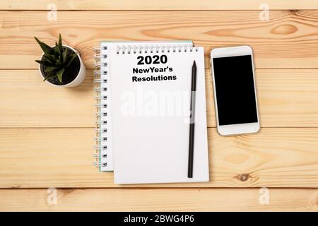 New year Concept - 2020 number and text on notepad. Smartphone, pen and cup of copy background. top view Stock Photo