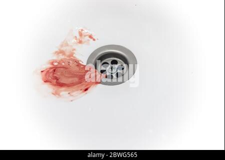 saliva with gum blood and toothpaste after brushing drains into the drain hole of the sink Stock Photo